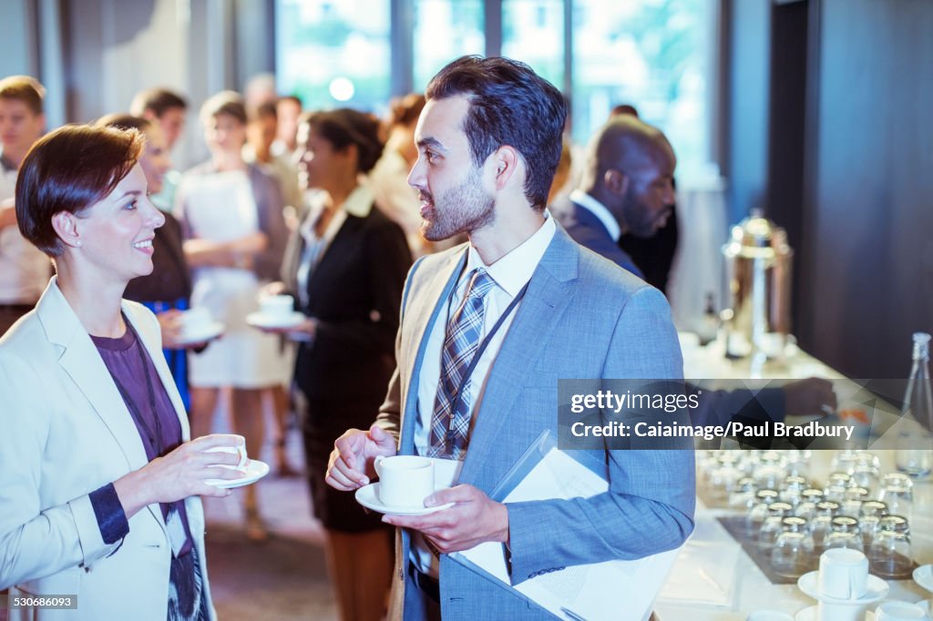 Portrait of man and woman talking in lobby of conference center during coffee break
