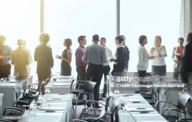 Gruppe von Menschen, die an den Fenstern des Konferenzraums stehen und während der Kaffeepause Kontakte knüpfen
