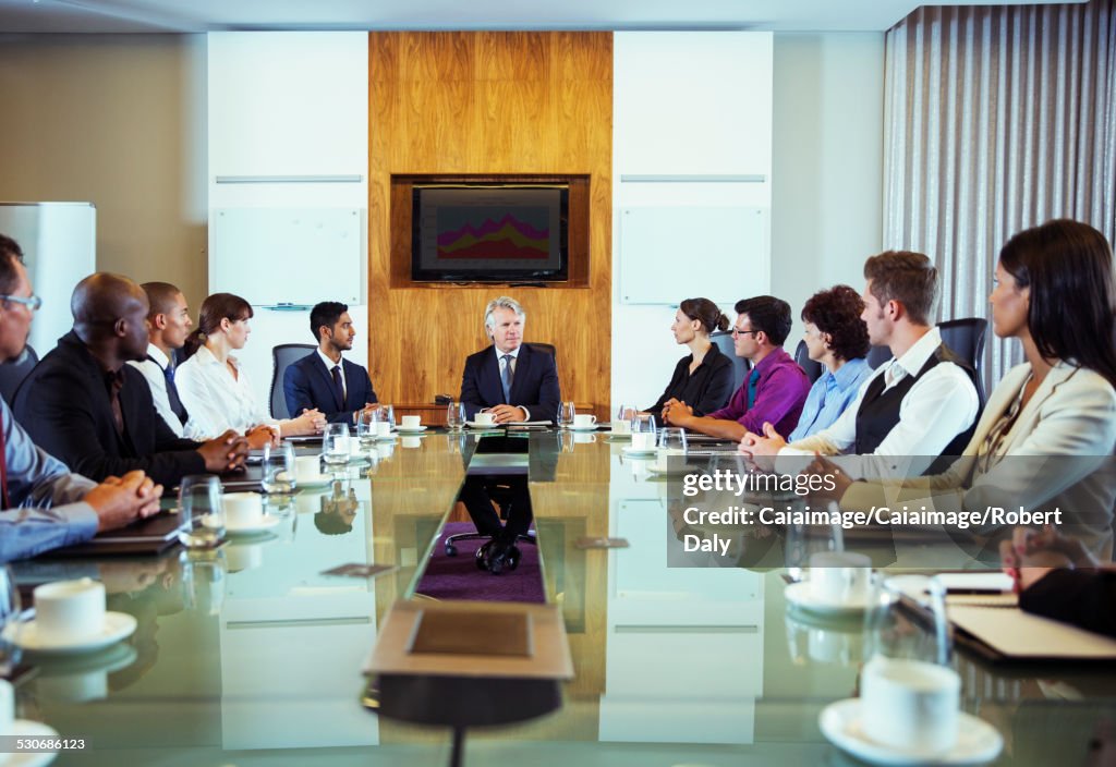 Konferenzteilnehmer betrachten Mann, der am Kopf des Konferenztisches sitzt