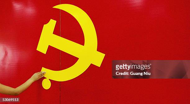 An outstrected hand touches the Hammer and Sickle logo at an exhibition promoting the Chinese Communist Party on June 15, 2005 in Beijing, China. A...
