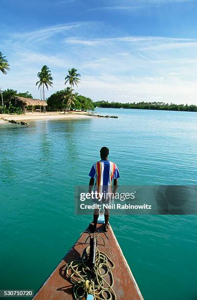 man standing on the bow of a boat - island hut stock pictures, royalty-free photos & images
