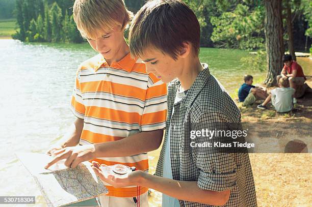 boys looking at map and compass - orientierungslauf landkarte gruppe stock-fotos und bilder