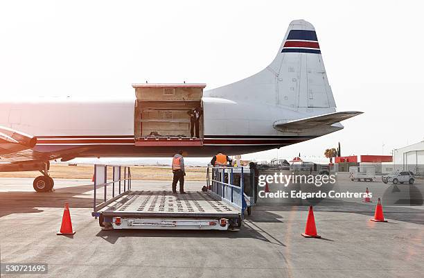 unloading cargo plane in an airport - frachtflugzeug stock-fotos und bilder