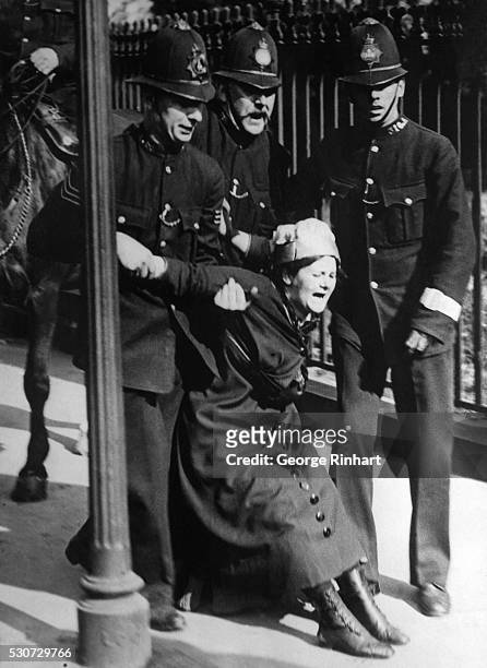 London, England: Three "bobbies" arrest a suffragette outside Buckingham Palace. Photograph, London, June 1914.