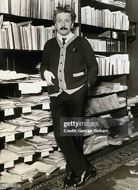 Albert Einstein leaning against shelves of scientific books and papers at his home in Berlin after his return from a visit to the United States,...