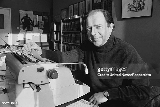 English writer, satirist and editor of Punch magazine, Alan Coren pictured sitting at a typewriter in the magazine's office in London on 21st...