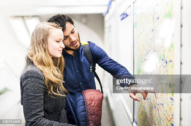 young couple finding their way in the metro - looking at subway map stock pictures, royalty-free photos & images