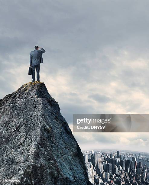 businessman looking at big city while standing on mountain top - person standing on mountain above city stock pictures, royalty-free photos & images