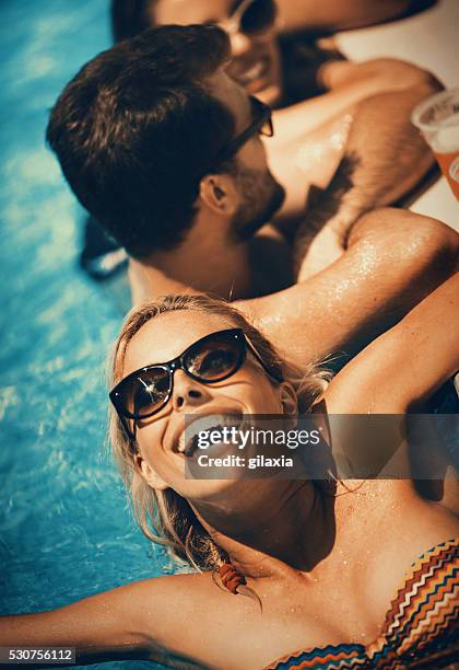 people enjoying drinks by the swimming pool. - couple on beach sunglasses stockfoto's en -beelden