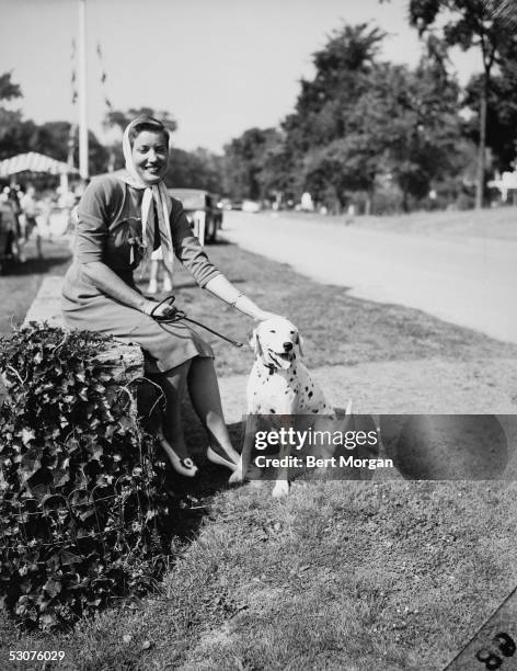 Eccentric American model and singer Edith Bouvier Beale sits on a low wall and pets her Dalmation, Easthampton, New York, July 28, 1944. Miss Beale...