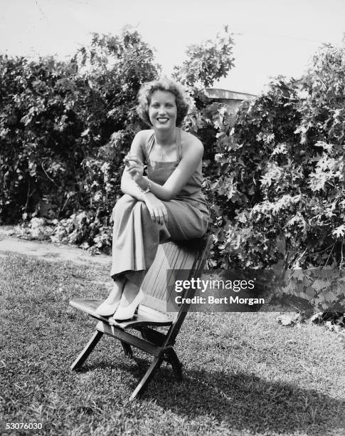 Eccentric American model and singer Edith Bouvier Beale sits on the back of a beach chair and smokes a cigarette, Village Fair at Easthampton, New...