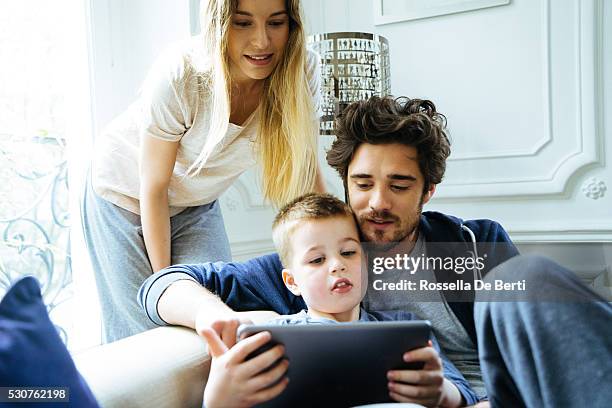 alegre joven familia observando un tableta digital juntos - naughty wife fotografías e imágenes de stock