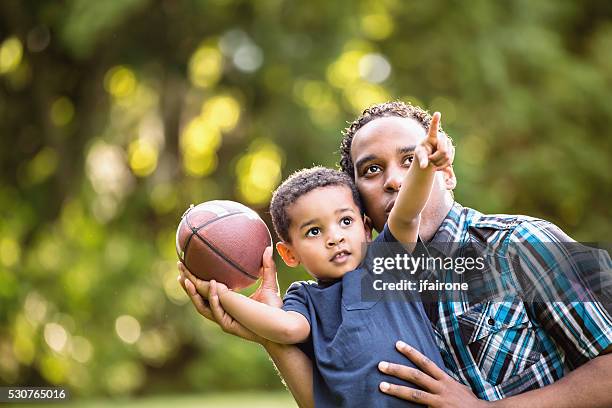 african american father and young son outdoors playing football - throwing football stock pictures, royalty-free photos & images