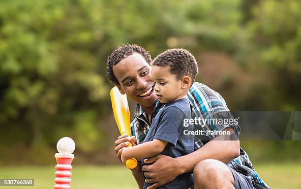 jungen afroamerikanischen vater und sohn spielen ball im freien t-shirt - baseball kid stock-fotos und bilder
