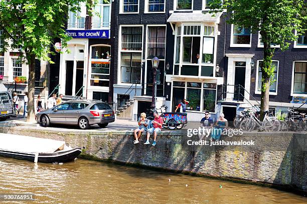 sitting at gracht voorburgwal - gracht amsterdam stockfoto's en -beelden