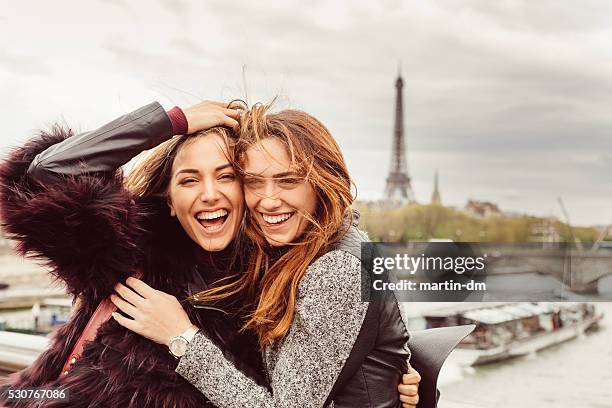 happy girls in paris against the eiffel tower - woman eiffel tower stock pictures, royalty-free photos & images