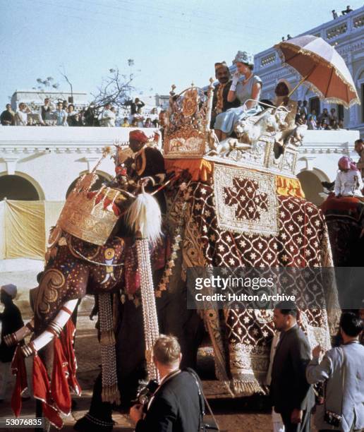 Queen Elizabeth II perches in a howdah on the back of an elephant at Benares, during her tour of India, 25th January 1961.