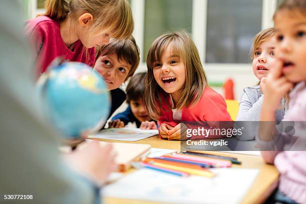 preschool teacher and children using globe. - learning stock pictures, royalty-free photos & images