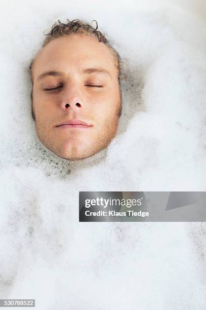 man submerged in bubble bath - surrounding ストックフォトと画像