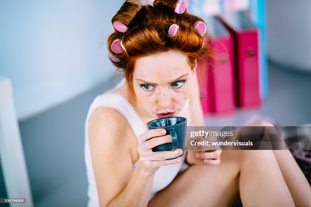 Woman With Curlers In Her Hair Drinks Coffee