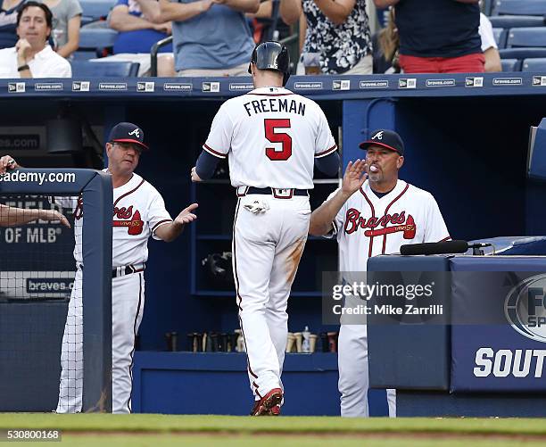 First baseman Freddie Freeman of the Atlanta Braves is congratulated by manager Fredi Gonzalez and bench coach Carlos Tosca after Freeman scores in...