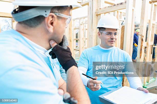 volunteer building contractor discussing plans with construction crew - instructions stock pictures, royalty-free photos & images