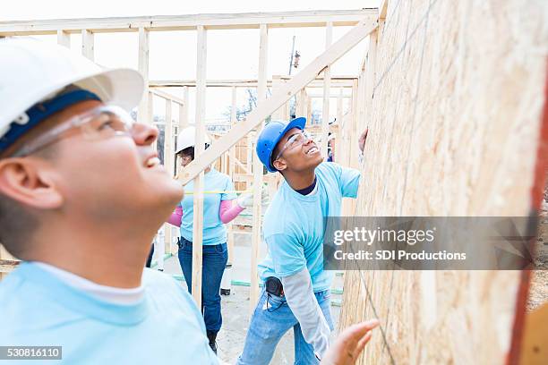 men move board while building charity home - volunteer building stock pictures, royalty-free photos & images