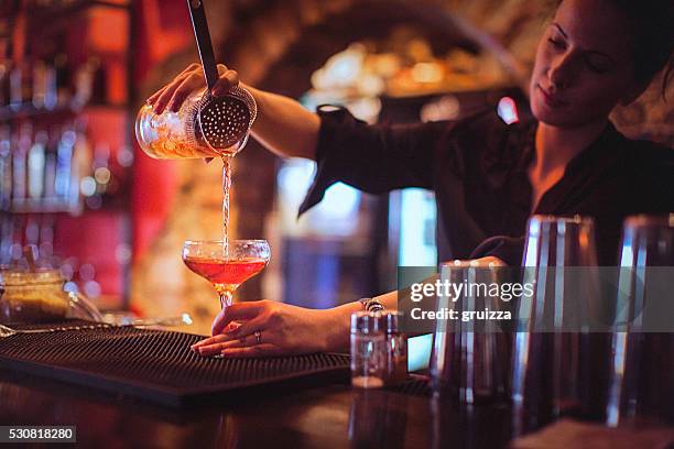 young female bartender pouring cocktails in a cocktail bar - cocktail making stock pictures, royalty-free photos & images