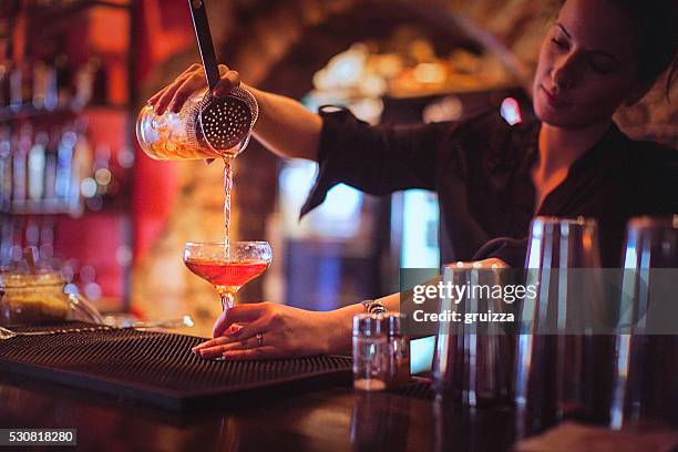 jovem empregado de bar servindo coquetéis em um bar de coquetéis - refreshment - fotografias e filmes do acervo