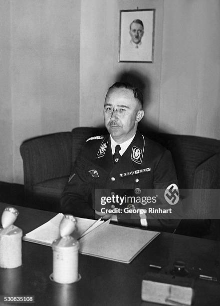 Heinrich Himmler, chief of the Gestapo, is shown seated at his office desk in Berlin. Photograph.
