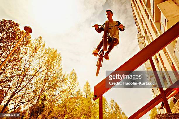 bmx biker performing a stunt over a railing - crossfietsen stockfoto's en -beelden