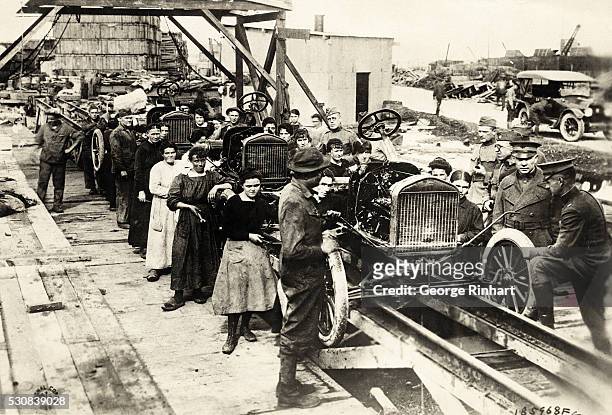Picture shows women working on an early outdoor Ford assembly line.