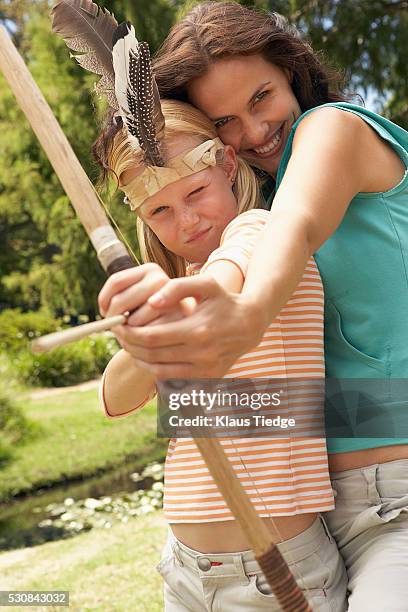 mother and daughter with a bow and arrow - archery feather stockfoto's en -beelden