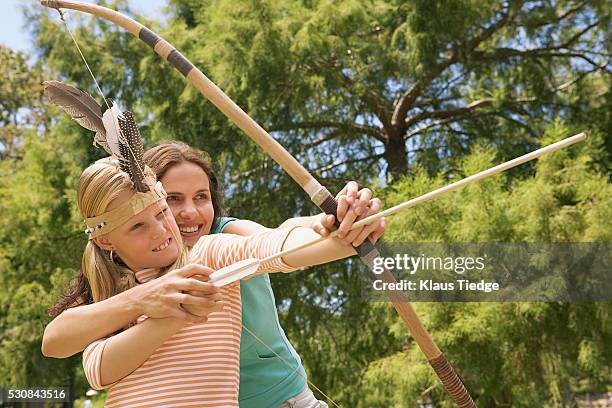 mother and daughter playing with a bow and arrow - archery feather stockfoto's en -beelden