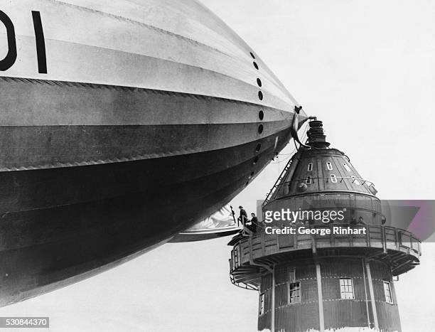 Members of Parliament are walking across the gangway from the mooring mast to the "R-101" dirigible.