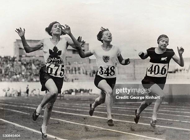 The finish of the eight heat of the 100-meter dash for women won by Myrtle Cook of Canada; second place taken by Miss Wilson of New Zealand and third...