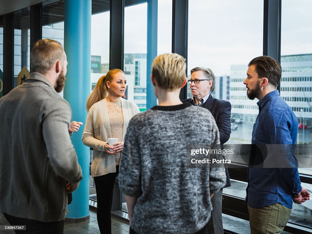 Businesspeople discussing by window in office