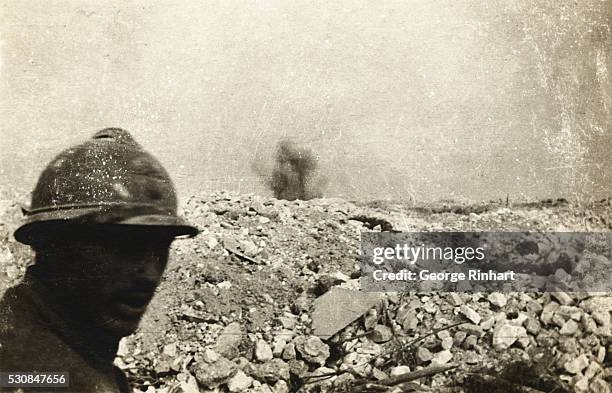 French soldiers stands in a trench as a shell explodes on the front line during World War I.