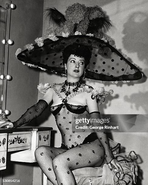 Gypsy Rose Lee, the famous burlesque queen and author, shown seated at the makeup table in her dressing room before a show. She is wearing a...