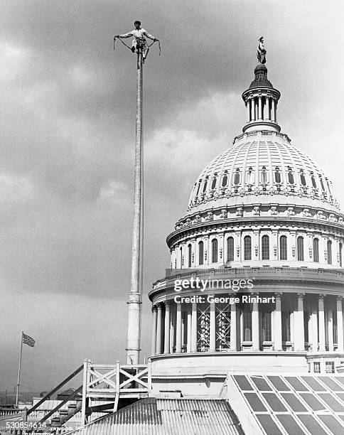 Washington, DC: A man sits on a flagpole outside of the Capitol Building in Washington, DC. Undated photograph circa 1925.