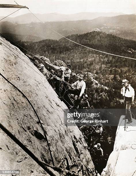 American sculptor Gutzon Borglum , who is leading the Mount Rushmore National Memorial project, stands on top of Mount Rushmore with a gang of his...