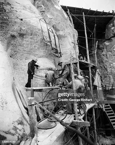 "Oculists" at work on Jefferson's eye. Gutzon Borglum is inspecting the operation. The four gigantic figures of the builders of the American empire-...