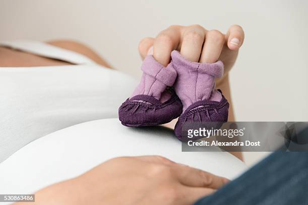 pregnant woman showing baby booties - alexandra dost stock-fotos und bilder