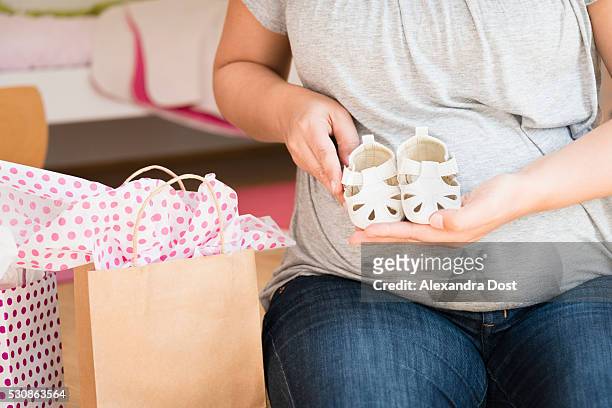 pregnant woman showing baby booties - alexandra dost stock-fotos und bilder