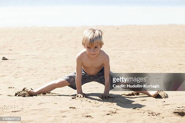 blond boy playing on beach - doing the splits stock pictures, royalty-free photos & images