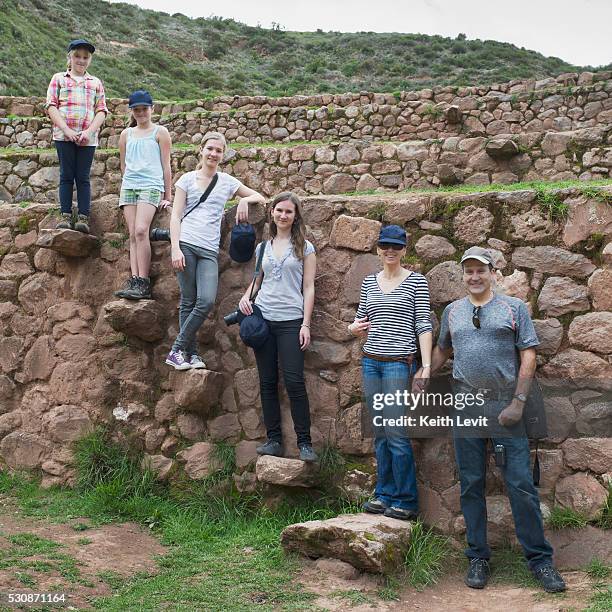 a family stands posing on rocks at the incan ruins; moray peru - moray inca ruin stock pictures, royalty-free photos & images