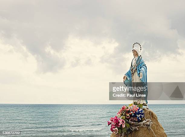 virgin mary statue on rock by ocean - jungfrau maria stock-fotos und bilder