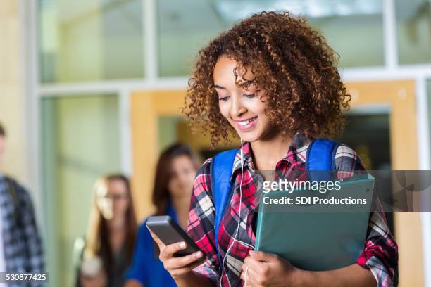 cute high school girl texting on smart phone between classes - beautiful college girls stock pictures, royalty-free photos & images