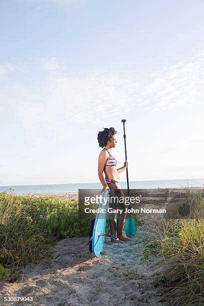 young woman resting with paddle board on beach. - juno beach florida photos et images de collection