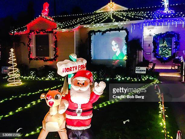 El Segundo, CaSanta and Rudolph the red nosed reindeer and a video screen projection are part of a private homes Christmas lights display on candy...